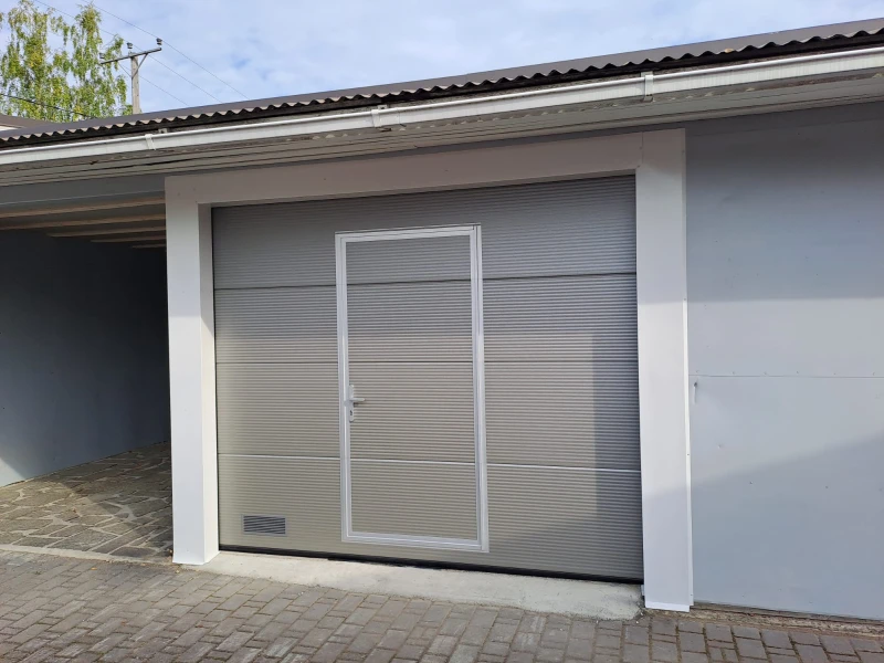 Autotallin nosto-ovi käyntiovella asennettuna — makroura hopea — JK-Ovet