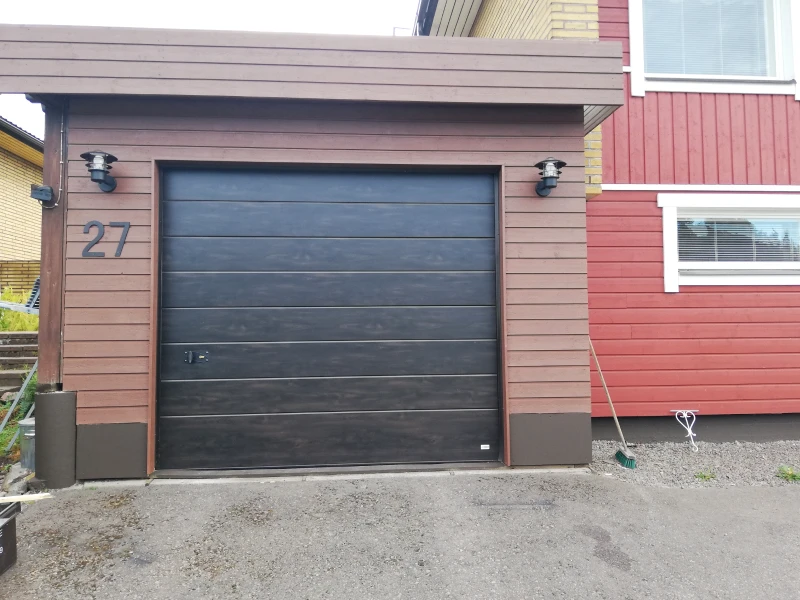 Autotallin nosto-ovi asennettuna Haminassa — puujäljitelmäpinta tumma tammi — JK-Ovet