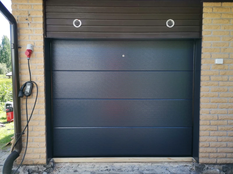 Autotallin nosto-ovi asennettuna Lahdessa — makroura tummanharmaa — JK-Ovet