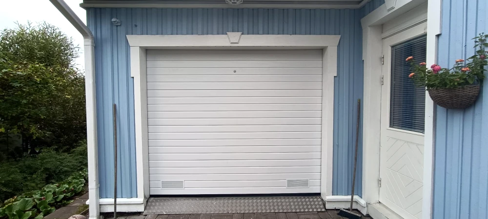 Autotallin nosto-ovi koristepaneloinnilla ja turkkipeltikynnyksellä — kapea vaakaura — JK-Ovet