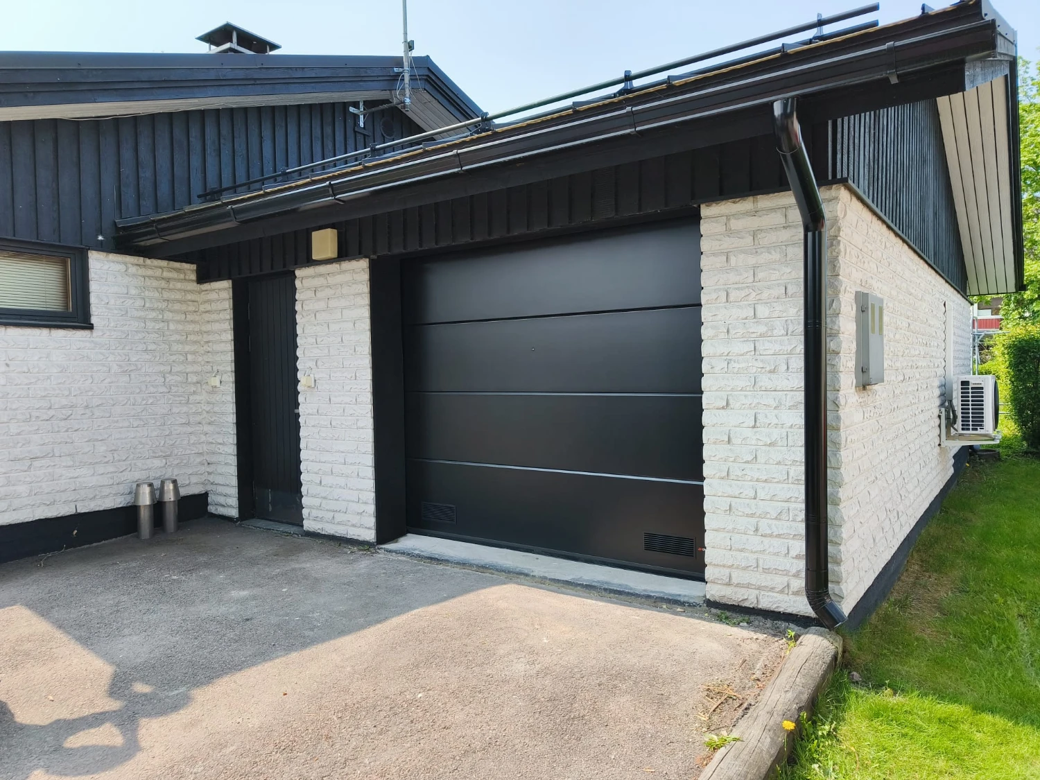 Musta yhtenäinen sileä nosto-ovi asennettuna Kotkassa — mustat peltipielet — JK-Ovet