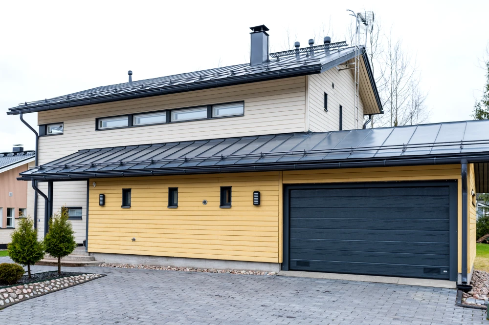 Harmaa autotallin nosto-ovi leveällä vaakauralla asennettuna Kouvolassa — Puunsyy — JK-Ovet